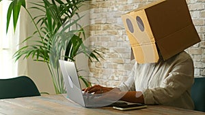 Home worker with carton box on his head. Anonymous people use laptop computer. Concept of doubts and problems with privacy online