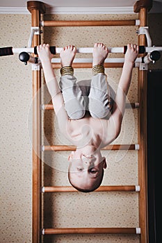 Home workout. The boy hangs head down on the horizontal bar