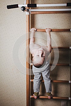 Home workout. The boy hangs head down on the horizontal bar