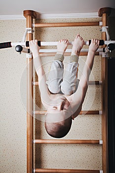 Home workout. The boy hangs head down on the horizontal bar