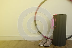 Home workout concept. Fitness, yoga, sport equipment - yoga mat, skipping rope, sport shoes and hula hoop - a large hoop spun