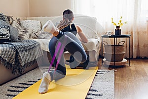 Home workout during coronavirus quarantine. Woman training using mat sport belt. Booty glutes building