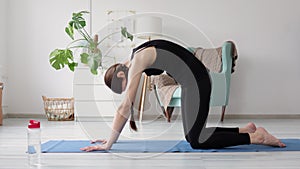 Home yoga, woman make cat cow pose on mat in living room. 20s slim female in sportswear