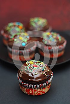 Homebaked Chocolate Muffins for Easter with colored Conffeti. Dark Background.