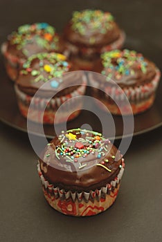 Homebaked Chocolate Muffins for Easter with colored Conffeti. Dark Background. Sweet Dessert for Breakfast.