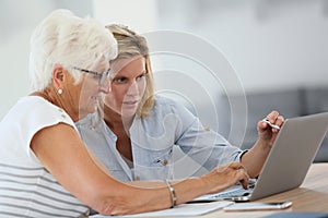 Homecarer and elderly using laptop