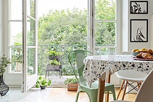 Homegrown herbs on a beautiful balcony outside a scandinavian dining room interior with a round table