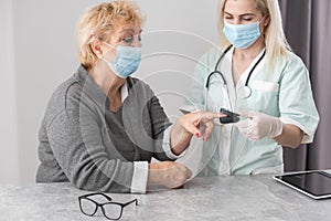 Homehealth care. Woman nurse in a medical mask help middle aged woman during during illness or pressure, female