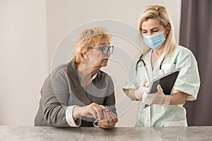 Homehealth care. Woman nurse in a medical mask help middle aged woman during during illness or pressure, female
