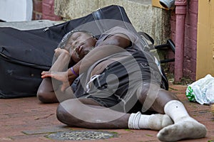 A homeless African American man sleeping on the street