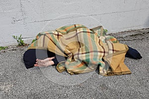 Homeless as he sleeps on the floor under a blanket