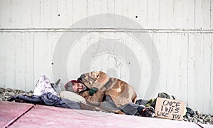 Homeless beggar man lying on the ground outdoors in city, sleeping. Copy space.