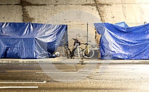 A homeless camp with bikes under a bridge during a rain storm