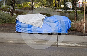 A homeless camp with blue tarp during a rain storm