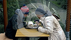 Homeless couple, man and woman eating leftovers from a table in a street cafe