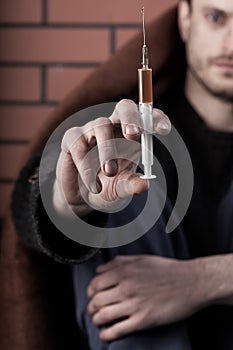 Homeless drug addict man with syringe in hand