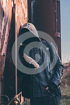 Homeless drunkard drinking alcohol next to old train wagon