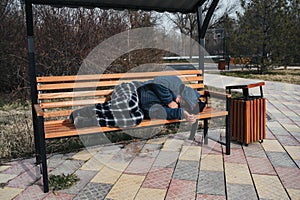 homeless elderly old man lies sleeping on park bench in autumn