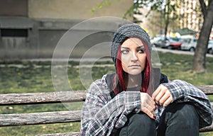 Homeless girl, Young beautiful red hair girl sitting alone outdoors on the wooden bench with hat and shirt feeling anxious and dep