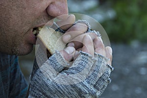 A homeless, hungry man greedily eats a piece of bread. Poverty, unemployment, hunger. Portrait