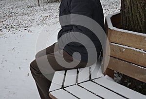 Homeless man, abandoned lonely and frail. When spending the night in a park on a snowy circle shape bench, it can get cold or caus