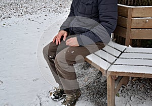 Homeless man, abandoned lonely and frail. When spending the night in a park on a snowy circle shape bench, it can get cold or caus