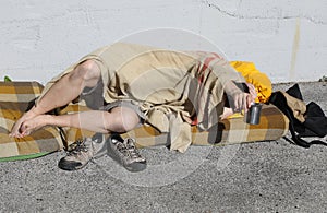 Homeless man begging passersby in a city street while resting un photo