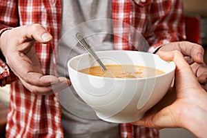 Homeless Man Being Handed Bowl Of Soup By Volunteer