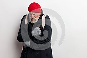 Homeless man bum dressed in black warm old big-sized clothing tries to warm up