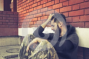 Homeless man drug and alcohol addict sitting alone and depressed on the street