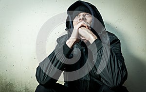 Homeless man drug and alcohol addict sitting alone and depressed on the street in winter clothes feeling anxious cold and lonely,