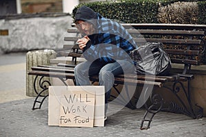 Homeless man in a durty clothes autumn city