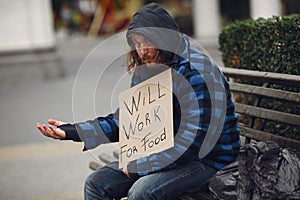 Homeless man in a durty clothes autumn city