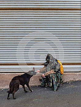 Homeless man giving food to the stray dog photo