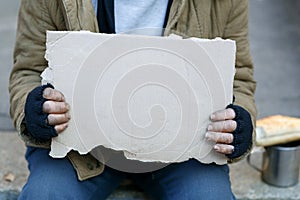 Homeless man holding a cardboard sign