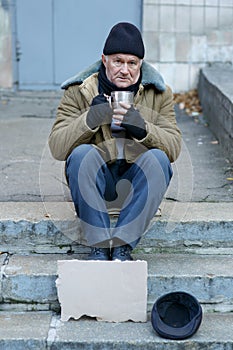 Homeless man holding his iron cup