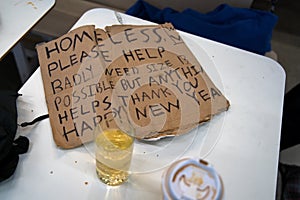 A homeless man`s sign sitting on a restaurant table