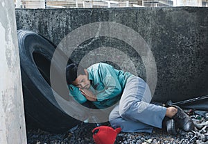 Homeless man sitting sadly beside the wall