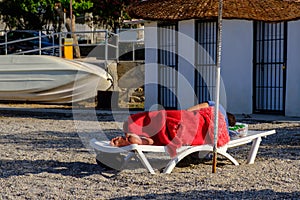 A homeless man sleeping on the beach.