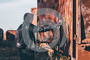 Homeless man spray painting old train wagon with aerosol can