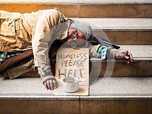 Homeless man on stairs begging for money