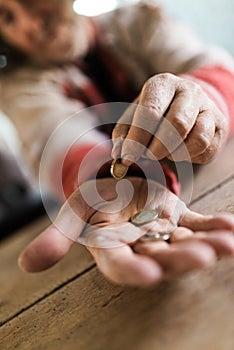 Homeless man in torn sweater counting his last euro coins