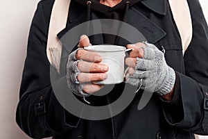 Recortado mendigo cubierta arriba en negro la ropa posesión taza de caliente té sobre el cálido por mi cuenta en frío 