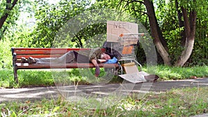 Homeless old man on the bench in city park.