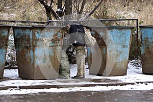 Homeless old man in search for food. Poor tramp hungry, rummaging for some food in garbage.