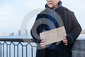 Homeless pensioner standing with paper in his hands