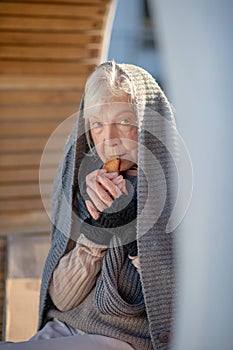 Homeless pensioner wearing scarf holding little cracker