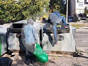 Homeless people seek food and valuables in a trash can. The disadvantaged louis carry a beggarly lifestyle. Sorting municipal