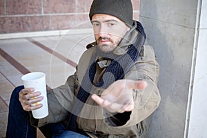 Homeless seated in the street and asking for charity