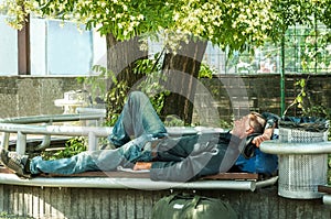 Homeless veteran. Poor hungry and tired homeless man ex military soldier sleep in the shade on the bench in urban city street soci